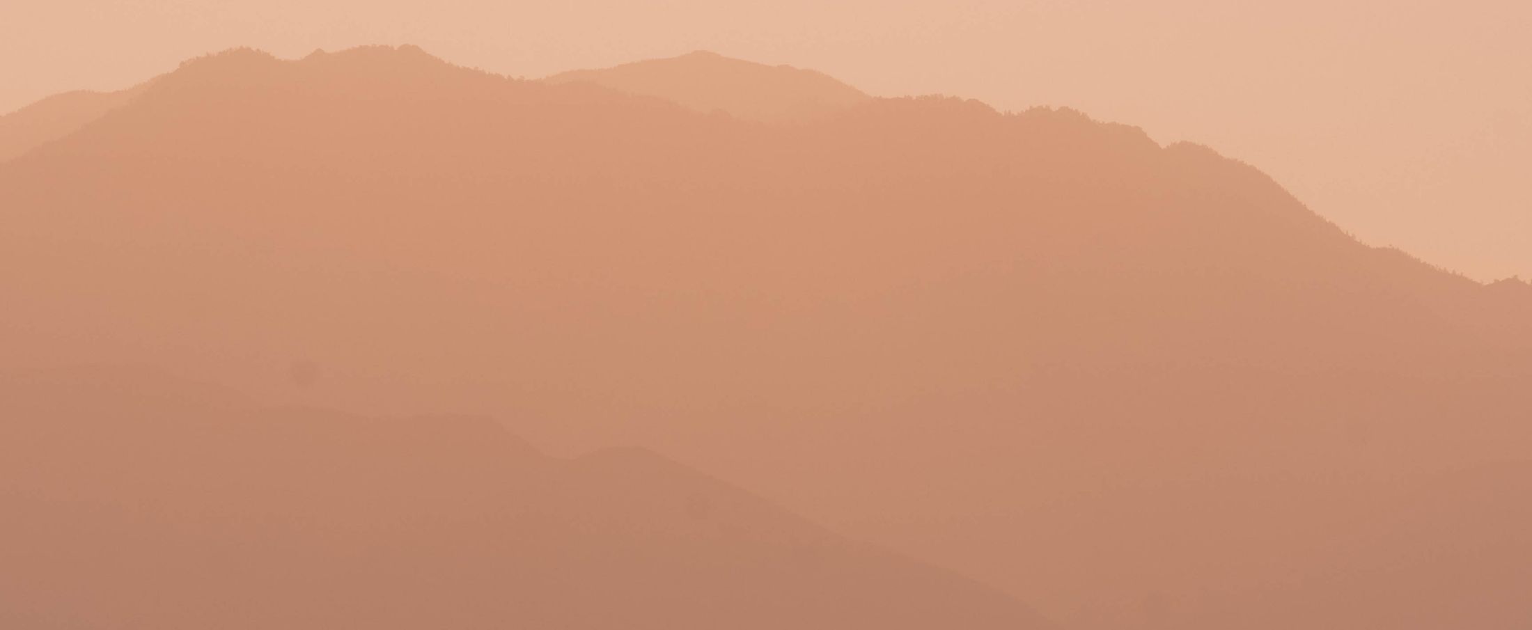 Layered mountains in soft peach hues.