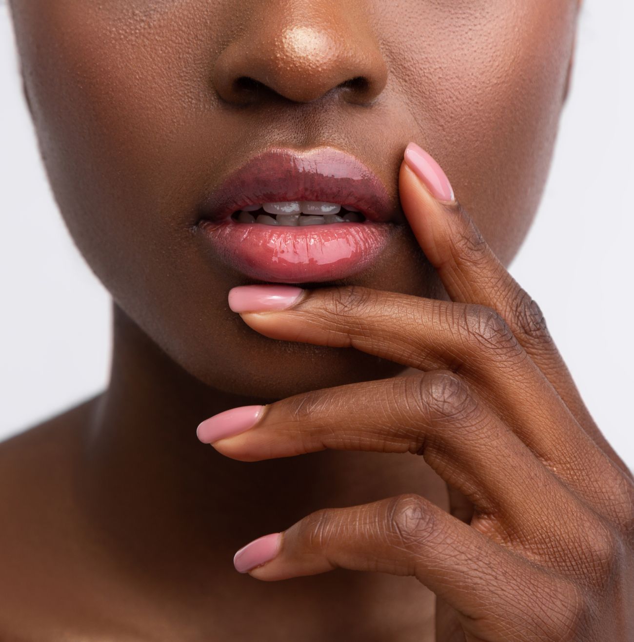 Close-up of lips and hand with polished nails.